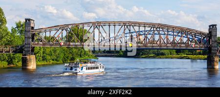 Crociere turistiche in barca sotto lo storico ponte di ferro sul fiume Elba a Magdeburgo, Germania, con un paesaggio di nuvole di cielo blu sullo sfondo. Sassonia-Anhalt Foto Stock