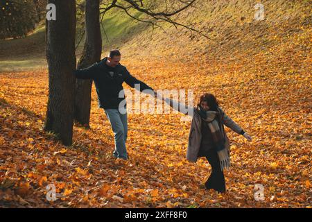 coppia di coniugi di oltre 50 anni, camminando attraverso il fogliame autunnale, in una calda giornata di sole, trascorrendo un fine settimana insieme. Foto Stock