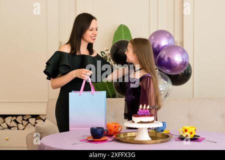 Mamma che fa un regalo di compleanno alla figlia durante i festeggiamenti. Foto Stock