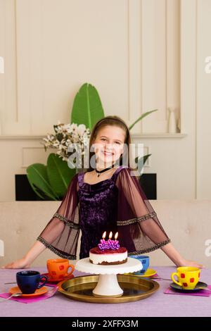 Una giovane ragazza con un vestito viola che festeggia il suo compleanno. Foto Stock