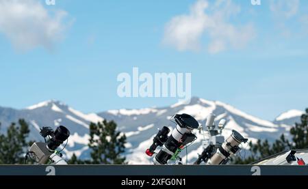 Telescopi sul tetto con montagne innevate sullo sfondo. Dispositivo utilizzato per osservare oggetti distanti per l'astronomia Foto Stock