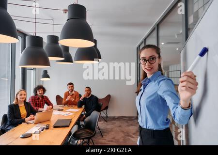 Donna d'affari che conduce un incontro con i colleghi di Modern Office. Foto Stock