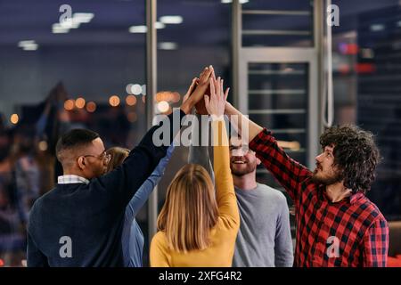 I giovani uomini d'affari multietnici che si divertono a celebrare il successo aziendale condiviso o la vittoria in carica. Sorridente multirazziale diversi dipendenti sentire Foto Stock