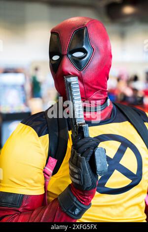 HARROGATE, REGNO UNITO 22 GIUGNO 2024. Primo piano ritratto di un cosplayer maschile vestito da Deadpool e in posa con una pistola e abiti Wolverine Foto Stock