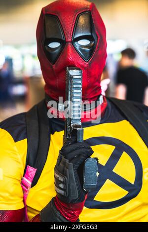 HARROGATE, REGNO UNITO 22 GIUGNO 2024. Primo piano ritratto di un cosplayer maschile vestito da Deadpool e in posa con una pistola e abiti Wolverine Foto Stock