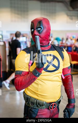 HARROGATE, REGNO UNITO 22 GIUGNO 2024. Primo piano ritratto di un cosplayer maschile vestito da Deadpool e in posa con una pistola e abiti Wolverine Foto Stock