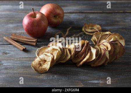 Mele secche fatte in casa con cannella, patatine di mele su fondo di legno. Delizioso e salutare spuntino Foto Stock