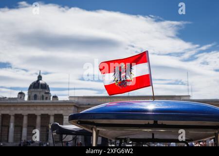 Bandiera austriaca con stemma su un veicolo turistico nella Heldenplatz di Hofburg a Vienna. Bandiera nazionale dell'Austria contro il cielo Foto Stock