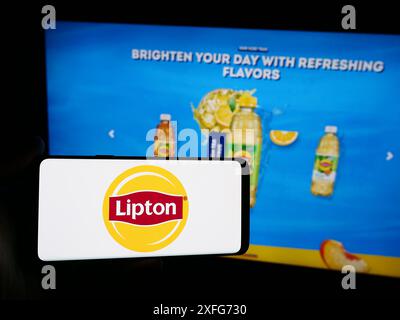 Persona con smartphone con logo del marchio Lipton davanti al sito Web. Mettere a fuoco il display del telefono. Foto Stock