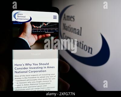 Persona che detiene un cellulare con pagina web della società statunitense di servizi finanziari Ames National Corporation con logo. Messa a fuoco al centro del display del telefono. Foto Stock