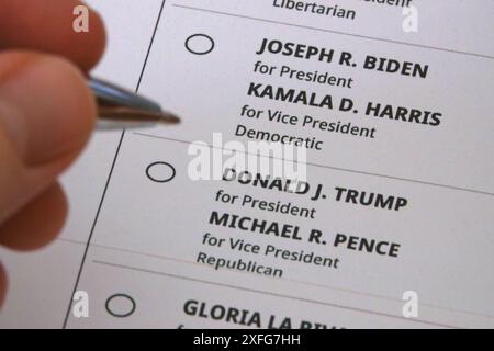 Los Angeles, CA / USA - 12 ottobre 2020: Una mano che tiene una penna si alza tra le bolle per votare per Joe Biden o Donald Trump in un ballottaggio per posta. Foto Stock