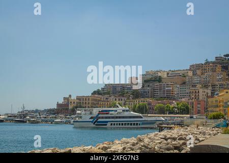 Vista del porto sul lungomare di Napoli e di una grande nave, colorati edifici italiani sullo sfondo, nel sud Italia Foto Stock
