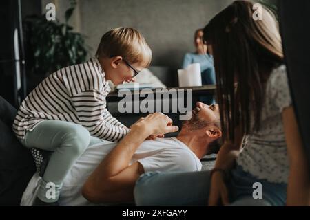 Padre felice che gioca con il figlio mentre si sdraia sul pavimento di casa Foto Stock