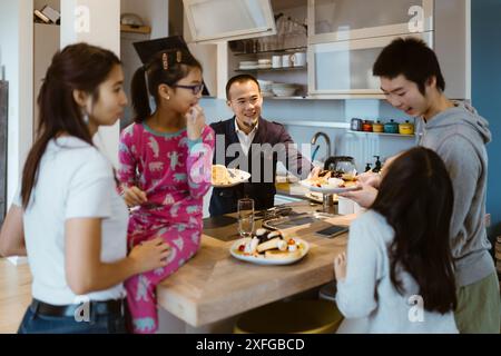 Una famiglia felice che ha dei pancake vicino al bancone della cucina a casa Foto Stock