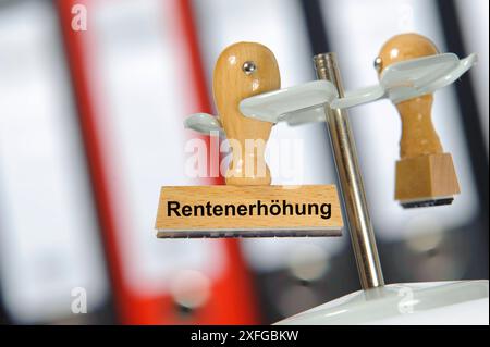 Rentenanpassung und Rentenerhöhung in einem Büro mit Aktenordner hängt ein Holzstempel mit der Aufschrift: Rentenerhöhung *** adeguamento delle pensioni e p Foto Stock