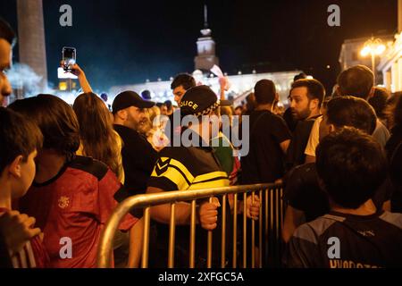 Tbilisi, Georgia. 3 luglio 2024. Un agente di polizia porta una recinzione metallica attraverso una folla per barricare l'area vicino al palco. La squadra di calcio georgiana ha visitato Tbilisi per celebrare un posto storico nella UEFA Champions League dopo aver vinto contro il Portogallo nella fase a gironi ma aver perso contro la Spagna nelle qualificazioni. Credito: SOPA Images Limited/Alamy Live News Foto Stock