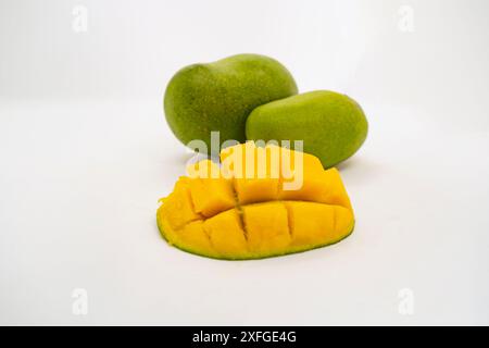 Mango verde dall'aspetto delizioso, fette di frutta tropicale tritate e intere in uno sfondo bianco isolato con cestino Foto Stock