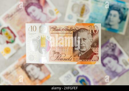 Nuova valuta britannica con re Carlo III, emessa per la prima volta nel giugno 2024 dalla Bank of England, Regno Unito. Sullo sfondo, banconote più vecchie con l'immagine della Foto Stock