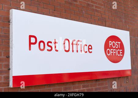 Primo piano dell'insegna isolata dell'ufficio postale (in rosso e bianco) sulla parete esterna di un ufficio postale del Regno Unito. Foto Stock