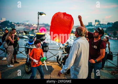 Durante São João la notte a Oporto, famiglie e amici si riuniscono per preparare i palloncini per il rilascio, una tradizione che simboleggia la buona fortuna e gli auguri per l'anno a venire. I palloncini illuminati creano uno spettacolo magico mentre si spostano nel cielo notturno. Foto Stock