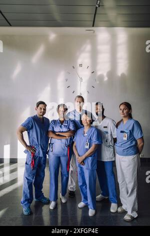 Ritratto di professionisti medici maschili e femminili in piedi insieme davanti al muro in ospedale Foto Stock