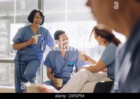 Felice team di medici maschili e femminili godendo durante la pausa caffè in ospedale Foto Stock