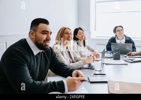 Donna d'affari felice seduta con colleghi nella sala riunioni dell'ufficio Foto Stock