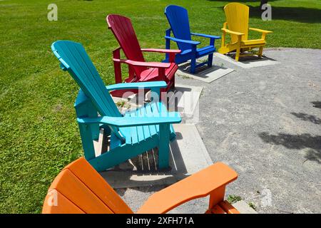 Sminuente vista prospettica delle sedie Adirondack multicolore nel parco pubblico Foto Stock