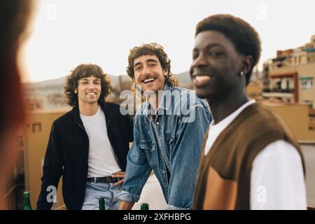 Ritratto di un uomo sorridente con amici maschi in festa sul tetto Foto Stock