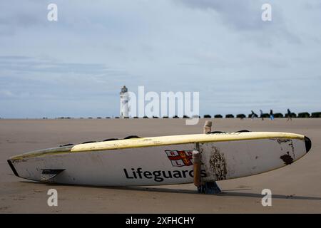 Paddle board bagnino sulla spiaggia di New Brighton Inghilterra Regno Unito. Faro di Perch Rock sullo sfondo. Foto Stock