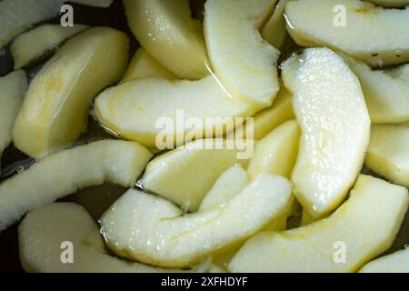 Vista ravvicinata delle fette di mela di gala in acqua salata. Preparazione per una torta. Foto Stock