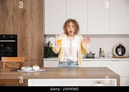 La giovane donna scioccata ha versato del succo sui suoi vestiti in cucina Foto Stock