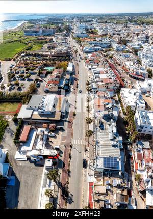 Vista aerea del centro di Ayia Napa con una strada vuota che la attraversa verso il mare in una giornata di sole. Cipro Foto Stock