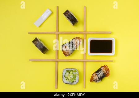 Sistemazione creativa di sushi e sashimi su sfondo giallo per un concetto di cucina giapponese. Foto Stock