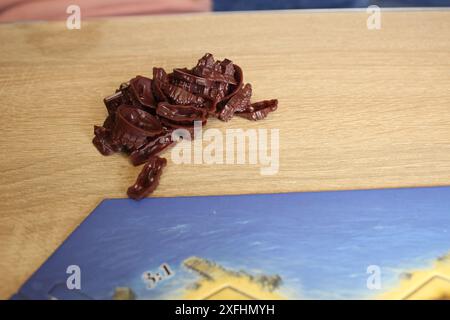 Mozyr, Bielorussia, 10 aprile 2024: brown meeple game elements on a beige background vicino al campo di gioco catan. Foto Stock