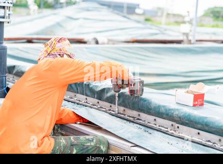 Il lavoratore utilizza una chiave a batteria per serrare il dado del laghetto di trattamento bordo della guarnizione in fabbrica. Foto Stock