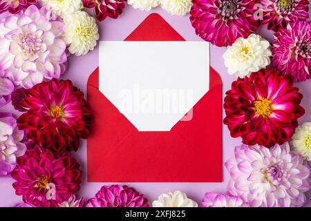 Layout creativo fatto di dalie di fiori con una busta vinosa con spazio per il testo. Biglietto d'auguri floreale. Design decorativo alla moda della natura. Posizione piatta. Foto Stock
