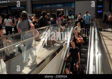 New York, Stati Uniti. 3 luglio 2024. La gente scende una scala mobile nella sala dei treni di Moynihan alla Penn Station. Il 3 luglio, un giorno prima delle vacanze del 4 luglio, molti viaggiatori a New York si dirigono verso i centri di trasporto. La quantità di viaggiatori durante questa settimana di vacanza ha causato la congestione nelle stazioni ferroviarie e degli autobus. Credito: SOPA Images Limited/Alamy Live News Foto Stock