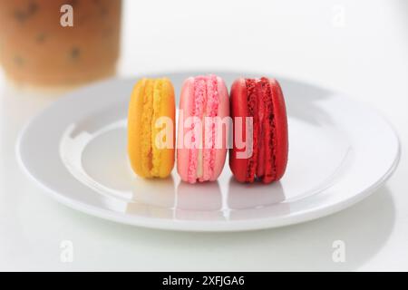 Macaron francesi dolci e colorati con tazza da caffè su tavolo bianco Foto Stock