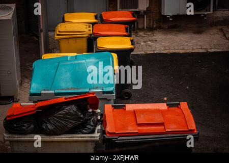 Cassonetti colorati e luminosi per la raccolta di rifiuti di vario genere in un cortile posteriore. Contenitori per rifiuti per la separazione di diversi tipi di materiali di scarto. Cestino. Foto Stock