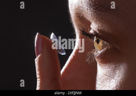 donna indossa lenti a contatto per primi piani visivi su sfondo scuro, foto macro di lenti a contatto, occhi astigmatici, lenti colorate Foto Stock