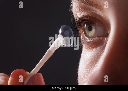 donna indossa lenti a contatto per primi piani visivi su sfondo scuro, foto macro di lenti a contatto, occhi astigmatici, lenti colorate Foto Stock