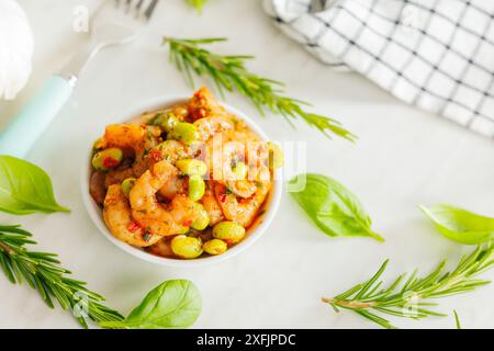 Insalata fresca con gamberetti e soia edamame nel recipiente su un tavolo bianco. Foto Stock