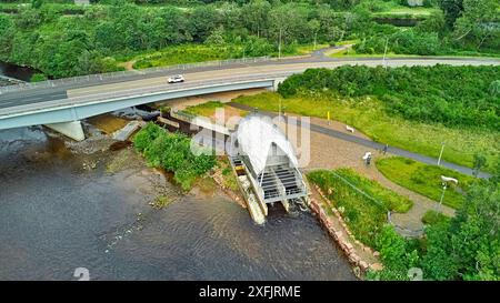 Hydro Ness il generatore idroelettrico in acciaio argentato sulle rive del fiume Ness in Scozia e un piccolo parco con cartelli informativi Foto Stock