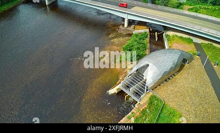 Hydro Ness il generatore idroelettrico in acciaio argentato sulle rive del fiume Ness in Scozia e A8082 Holm Mills Bridge Foto Stock