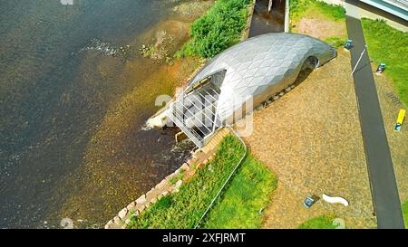 Hydro Ness il generatore idroelettrico in acciaio argentato sulle rive del fiume Ness in Scozia e piccolo parco con cartelli informativi Foto Stock
