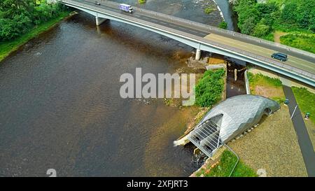 Hydro Ness il generatore idroelettrico in acciaio argentato sul fiume Ness Scozia e A8082 Holm Mills Bridge Foto Stock