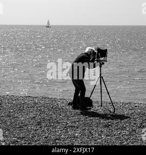 Un fotografo a Eastbourne Beach che scatta una foto con una fotocamera a lastra su un treppiede Foto Stock