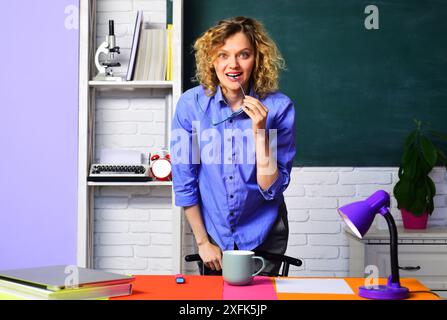 Concetto educativo. Insegnante sorridente, docente o educatore che impartisce lezioni agli studenti in classe. Insegnante universitario o tutore universitario vicino a blackbo Foto Stock