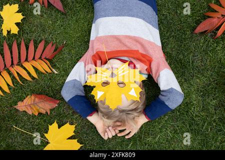 Ciao, Autunno. foto d'atmosfera stagionale. ama l'autunno e idee interessanti per la creatività. il bambino giace sull'erba e si nasconde dietro un Foto Stock